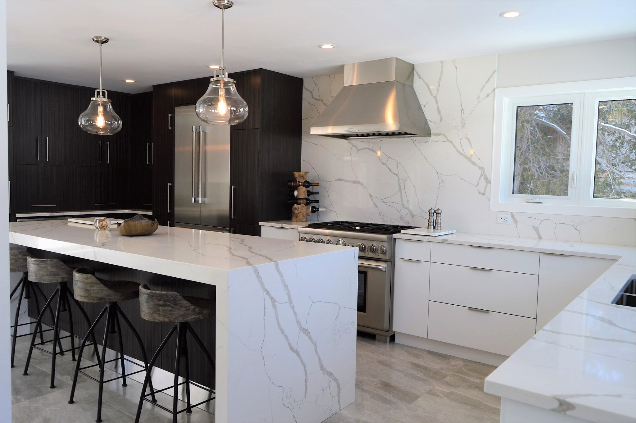 Modern kitchen with marble waterfall island and custom dark cabinetry by TCM